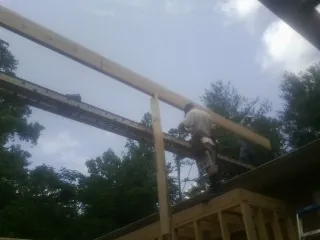 Carpenter setting a ridge beam over a new addition frame — Ice Dam Removal by Roofing Brothers in Represa