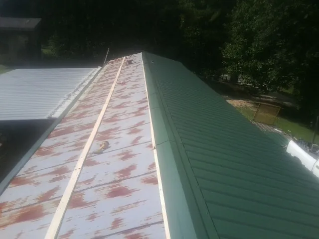 Old rusted panels beside newly installed green metal roofing — Wind Damage Roof Repair by Roofing Brothers in Represa