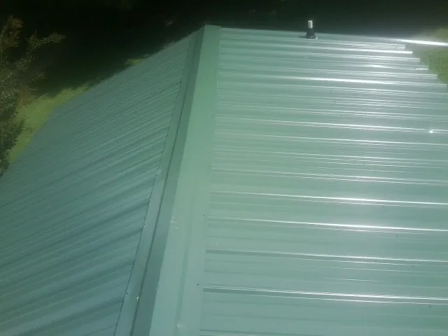 New green metal panels meeting at the ridge of a roof — Flat Roof Repair work by our crew in Represa