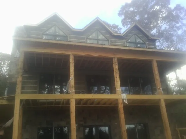 Dormers and porch framing on a large log home under construction — Roof Coating work by our crew in Represa