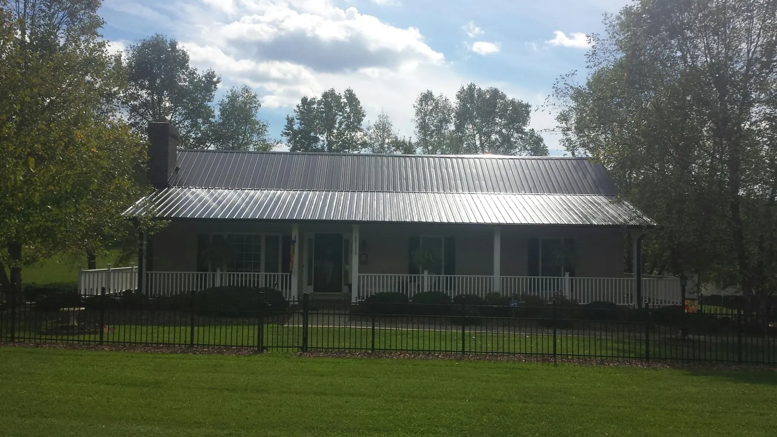 Gray metal roof on a brick ranch with a full width front porch — Gutter Guard Installation work by our crew in Represa