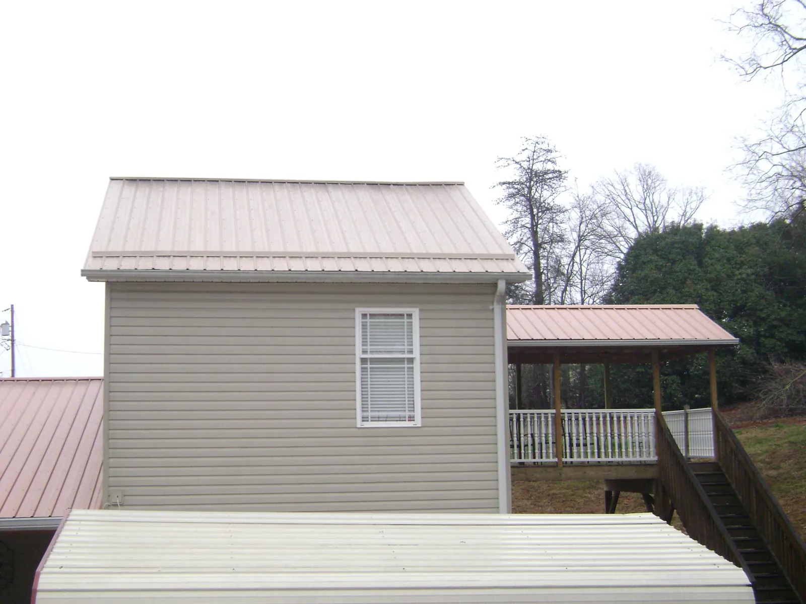 Tan metal roofs on a two story addition and attached porch, from a Roof Replacement job in Represa